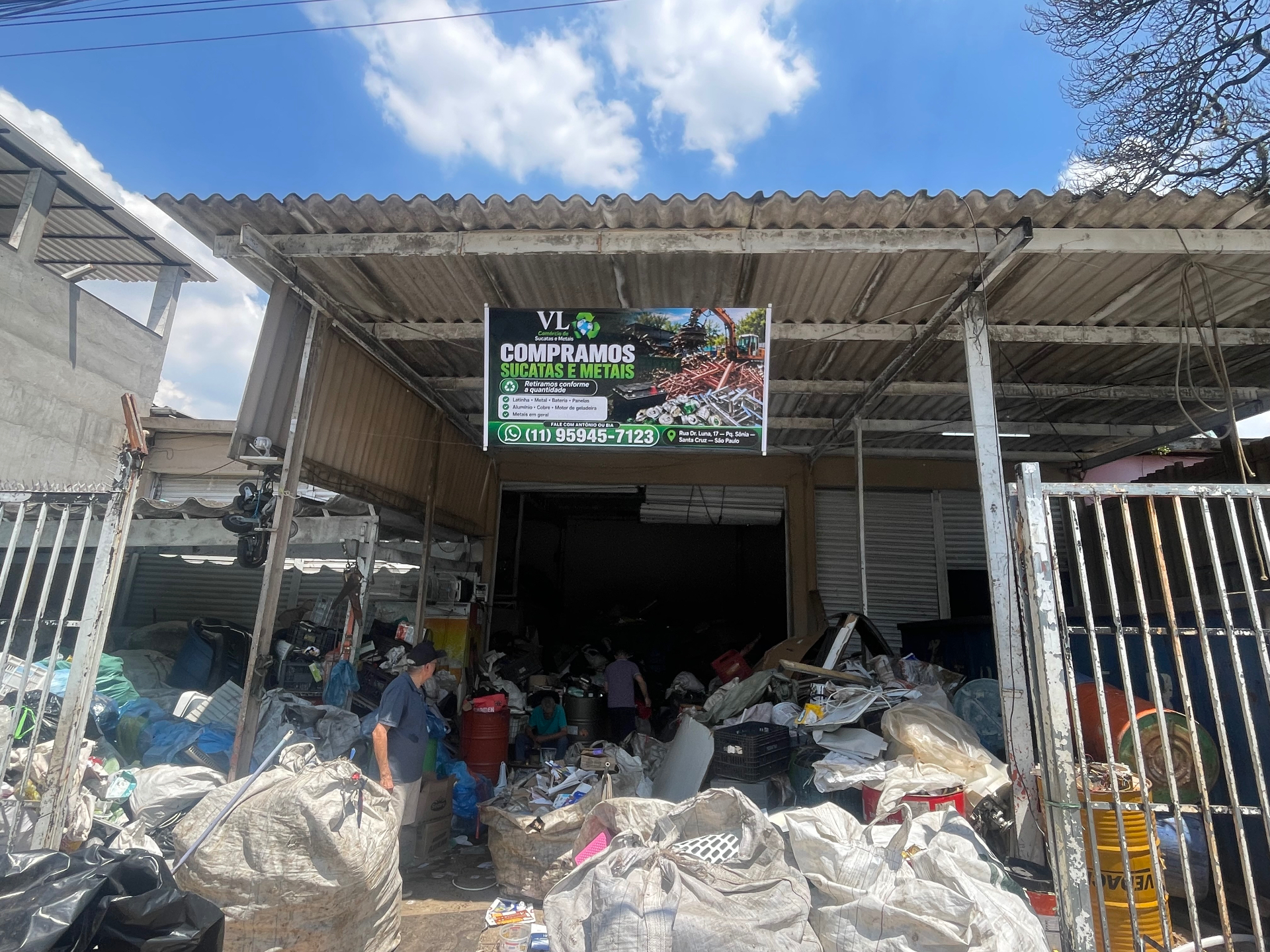 Fachada da VL Comércio de Sucatas e Metais, com a placa da empresa e a entrada do local